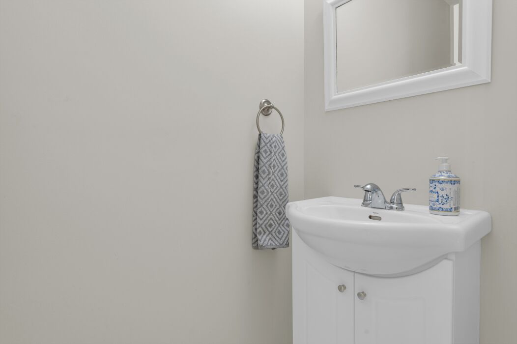 A bathroom with a white sink, a mirror, and a towel rack.