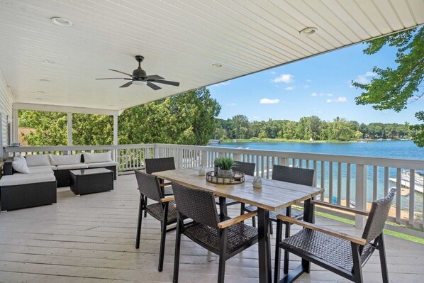 Une terrasse extérieure couverte, équipée d’une table et de chaises, d’un canapé et d’un ventilateur de plafond.
