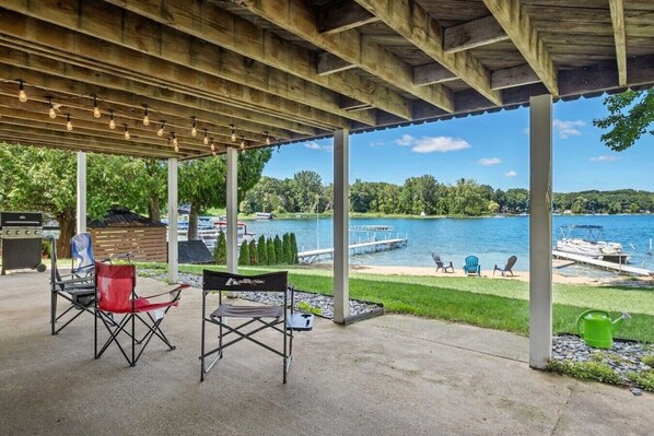 An outdoor patio with a covered area, a grill, and chairs.