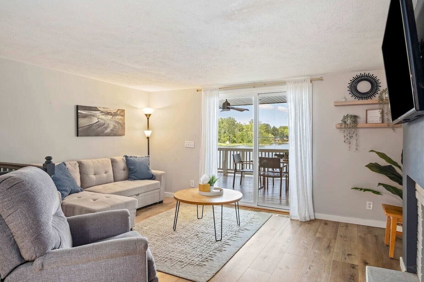 Ett vardagsrum med en soffa, ett soffbord och utsikt över en balkong med utemöbler.