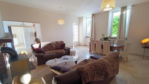 A spacious living room with a brown leather sofa, a coffee table, and a dining area with a table and chairs.