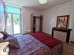 Un dormitorio con cama, una silla, un armario y un cuadro en la pared.