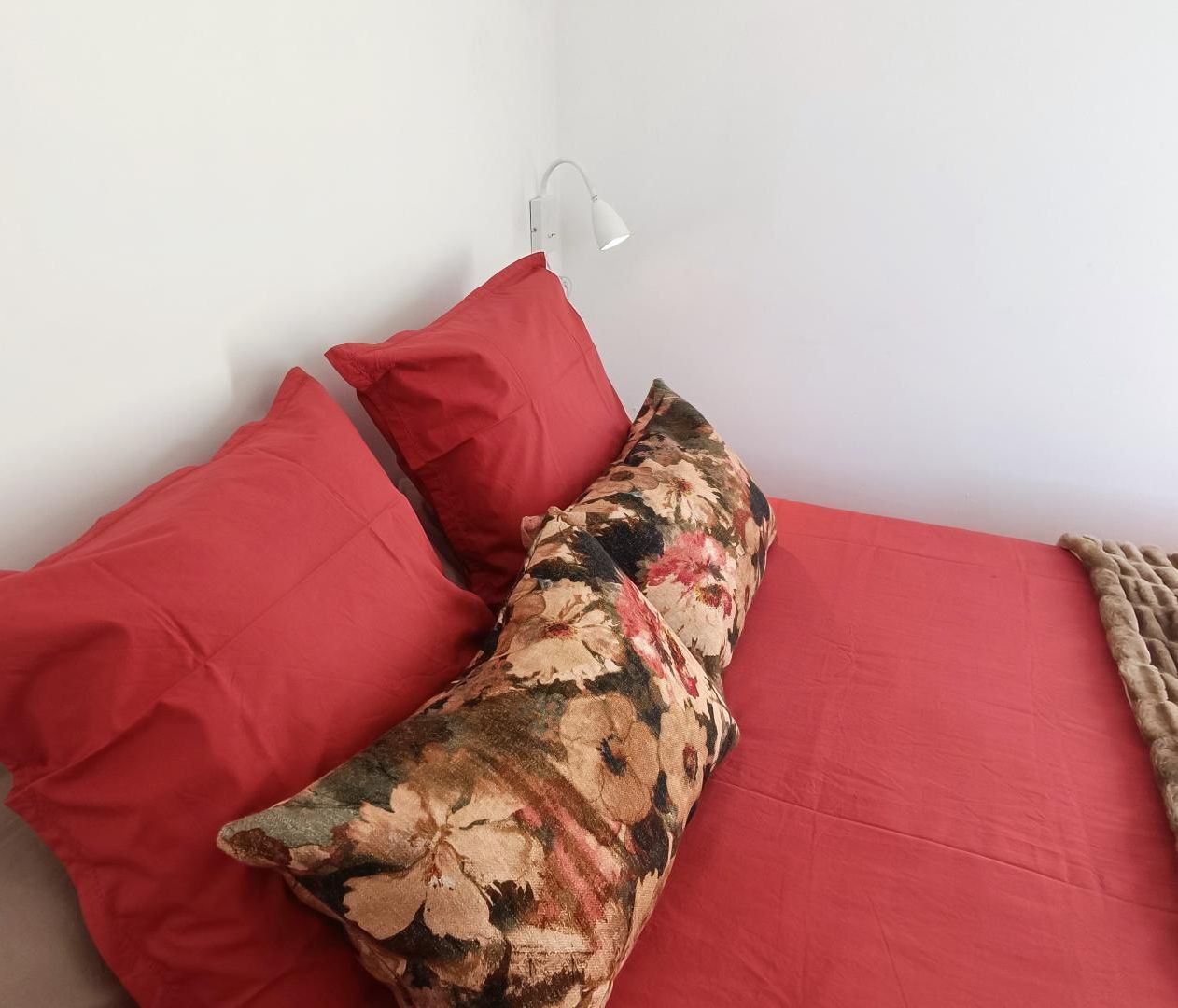 Una cama con ropa de cama roja y una almohada estampada.