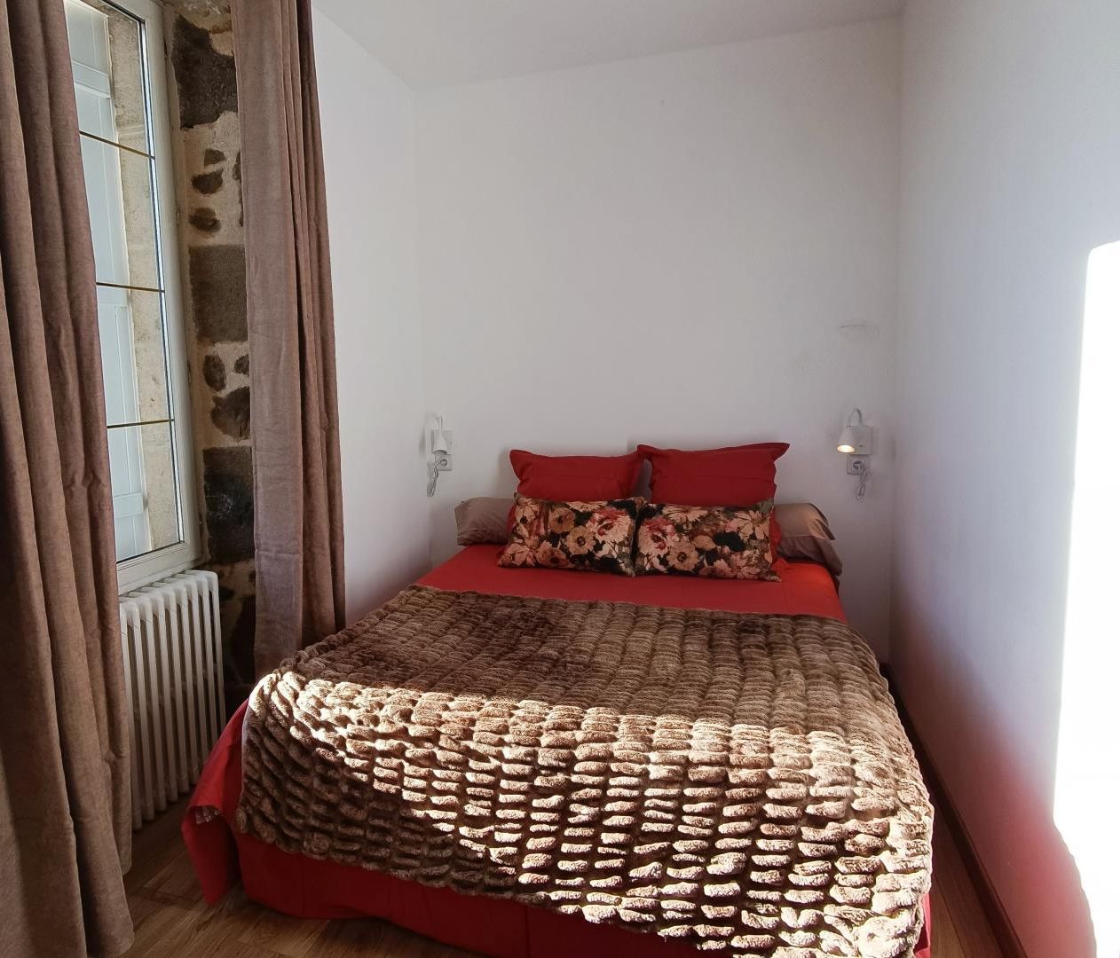 Une chambre à coucher avec un lit, des rideaux, un radiateur et une fenêtre.