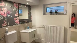 A bathroom with a toilet, sink, and mirror. There is a window above the sink and a radiator on the wall. - Quiet studio - charming & close to the city by bus (Bissendorf)