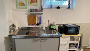 A compact kitchen with a stainless steel sink, a microwave, and a small window above the sink. - Quiet studio - charming & close to the city by bus (Bissendorf)