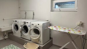 A laundry room with two washing machines, a sink, and an ironing board. - Quiet studio - charming & close to the city by bus (Bissendorf)