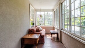 A sunlit room with a wooden bench, a cushioned sofa, and a small table.