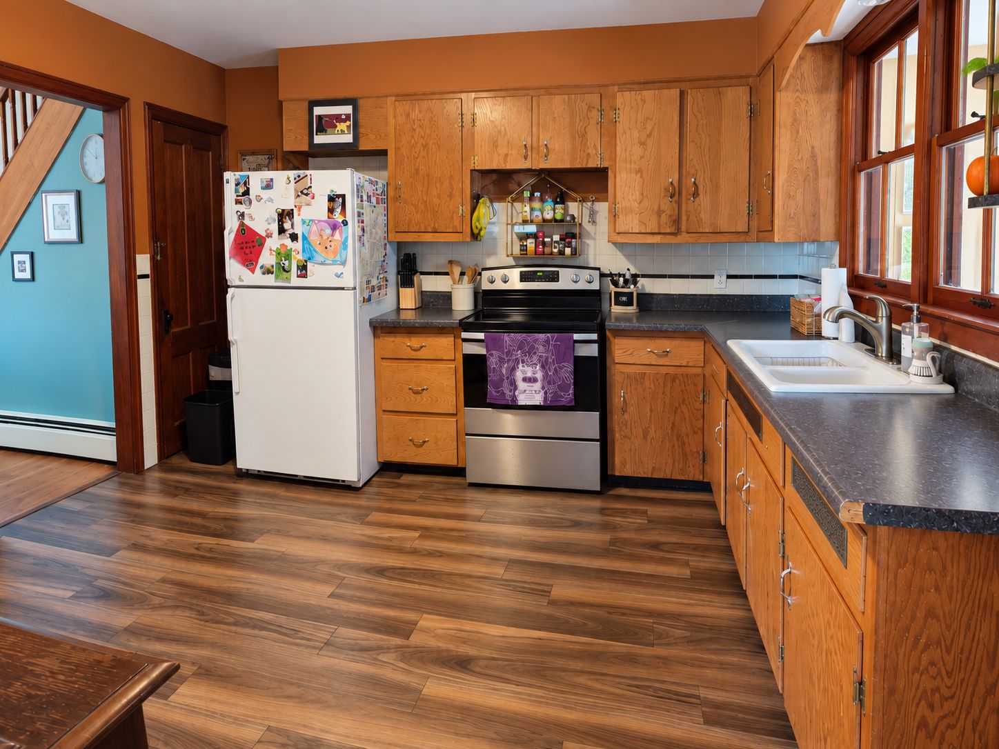 A kitchen with wooden cabinets, a refrigerator, a stove, and a sink.