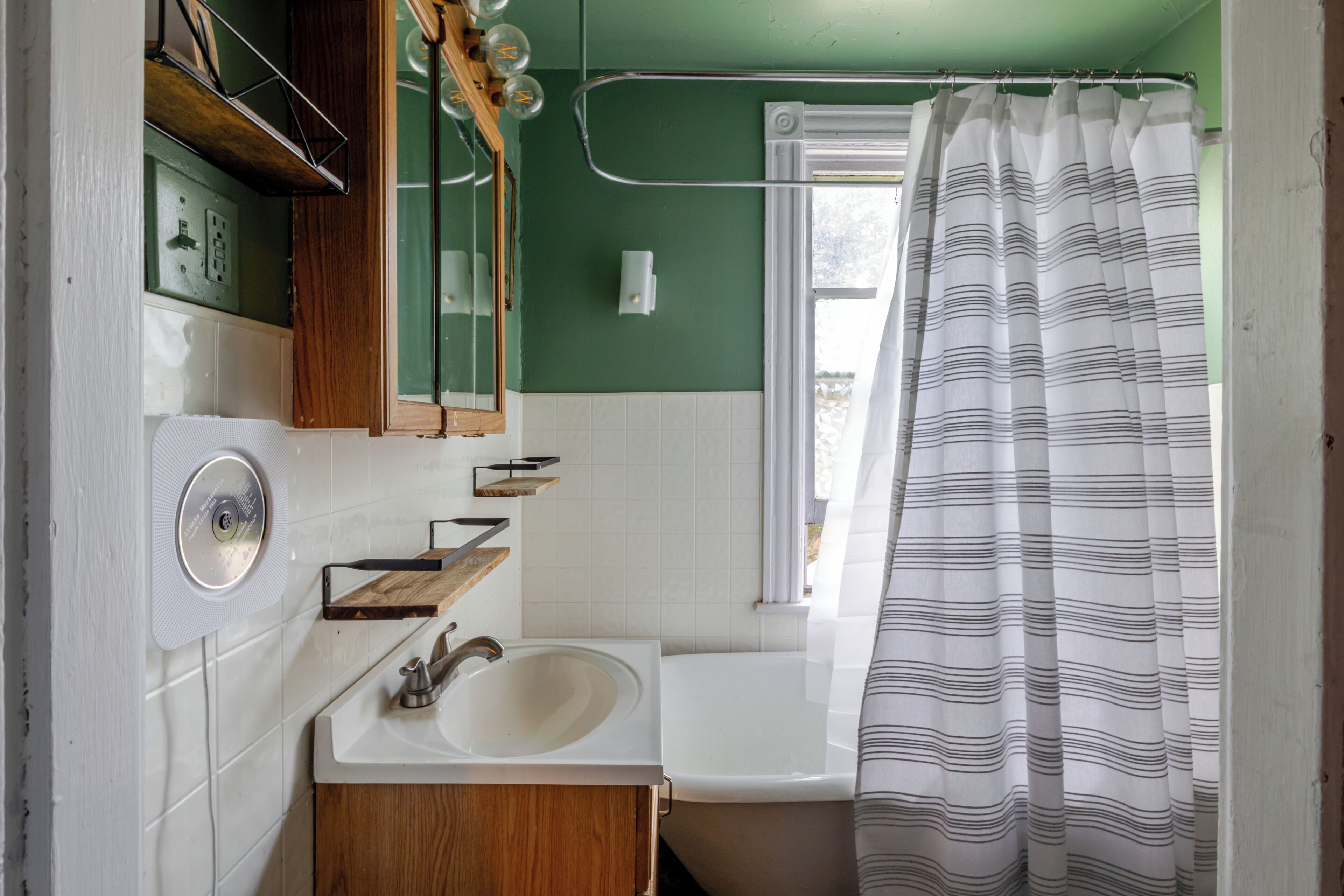 A bathroom with a sink, mirror, and shower curtain.