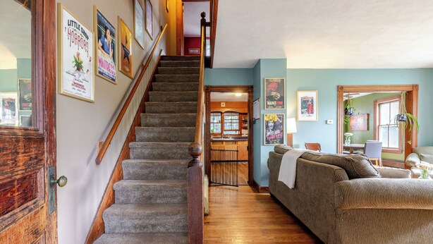 A staircase leading to a second floor, a living room with a sofa, and a kitchen area.