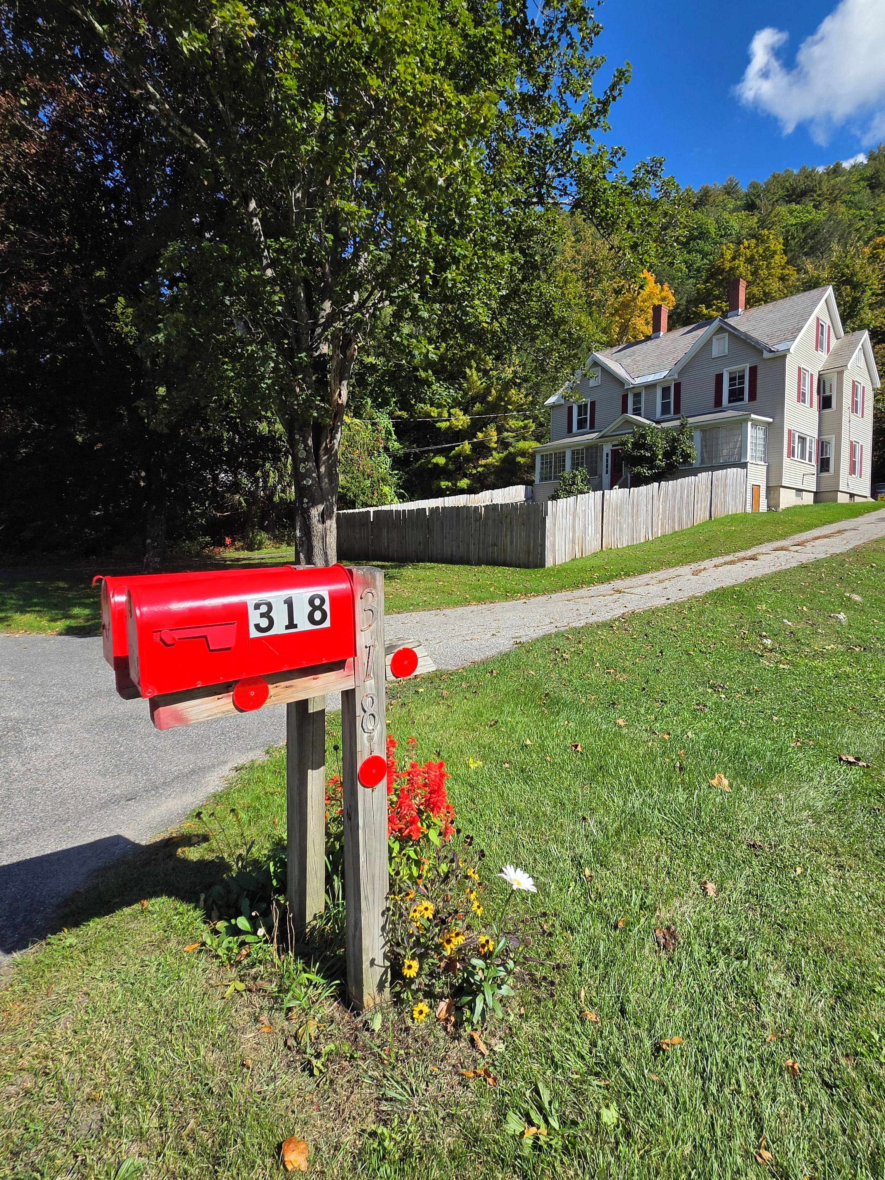 A mailbox with the number 318, a wooden fence, and a house in the background.