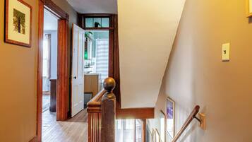 A staircase with a wooden handrail and a white wall with a light switch.