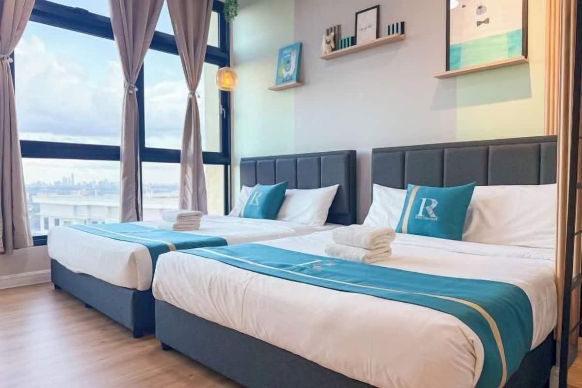 Een hotelkamer met twee bedden, uitzicht over de stad en een raam met gordijnen.
