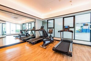 Een sportschool met loopbanden, een hometrainer en een roeiapparaat.