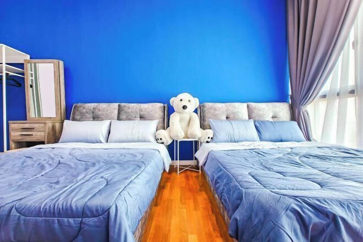 Een slaapkamer met twee bedden, een grote knuffelbeer, een spiegel en een kledingkast.