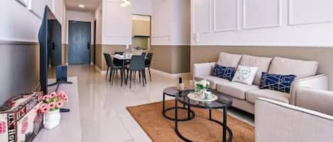 A modern living room with a sofa, coffee table, and a dining area with chairs and a table.