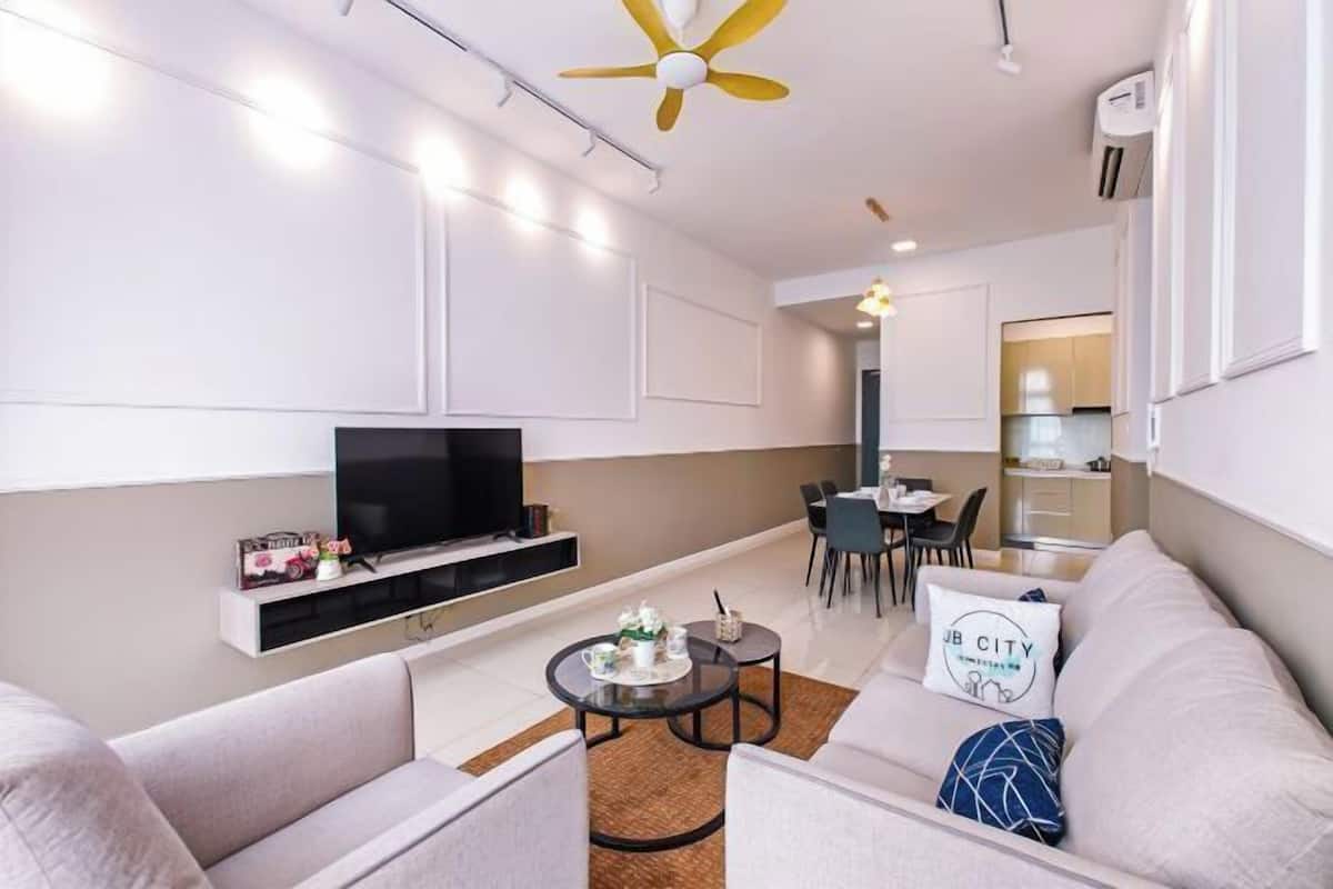 Een moderne woonkamer met een flatscreen televisie, bank, salontafel en een eethoek.