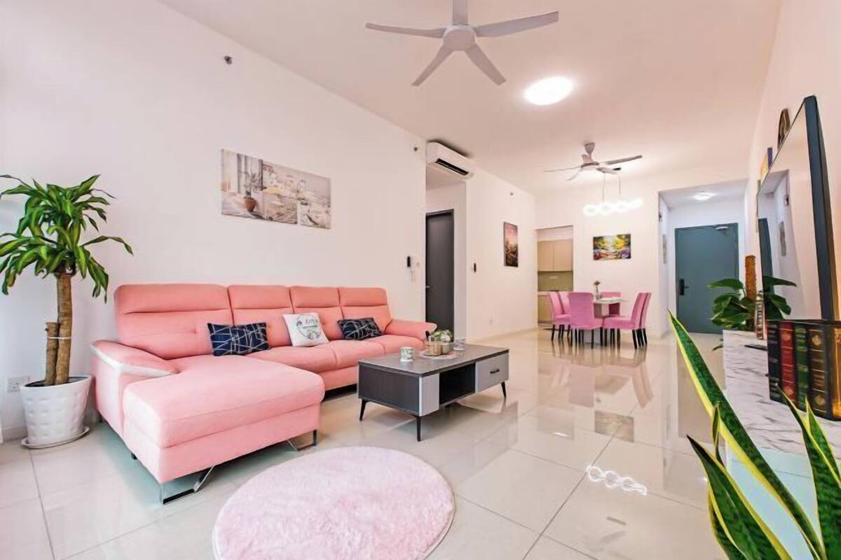 Een moderne woonkamer met een roze bank, een bijzettafeltje en een eethoek met roze stoelen.
