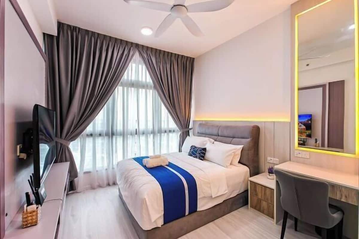 Een hotelkamer met een bed, bureau, stoel, plafondventilator en een grote spiegel.