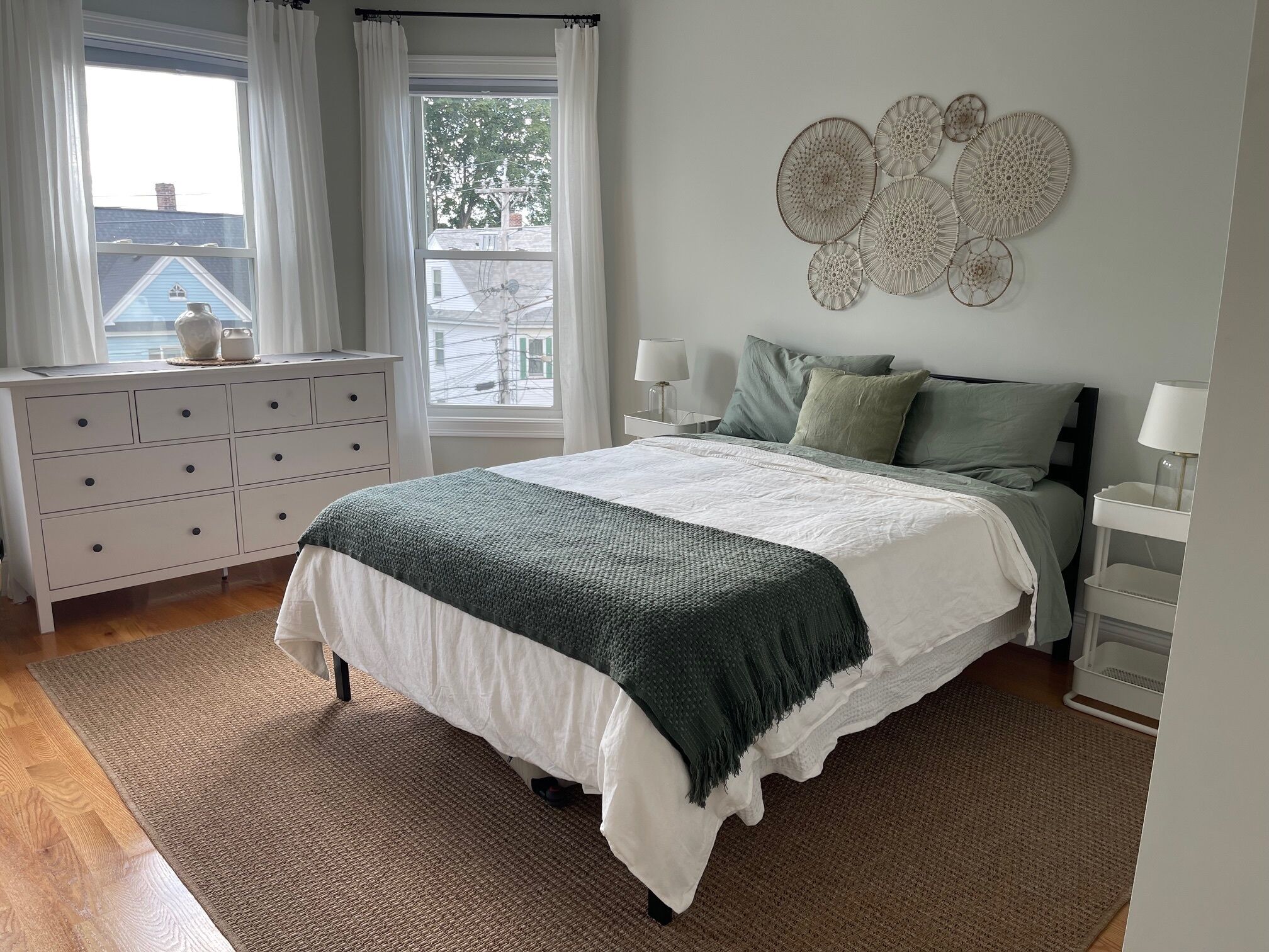 A bedroom with a bed, a dresser, a window with curtains, and wall decor.