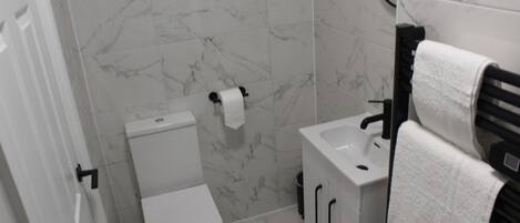 A bathroom with a toilet, sink, and towel rack.
