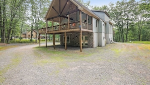 A two-story lodge with a stone foundation, a wooden deck, and a large porch. - Spa-Like Rustic Retreat In Nature With Glass Barrel Sauna, Hot Tub & Pond! (Albrightsville)