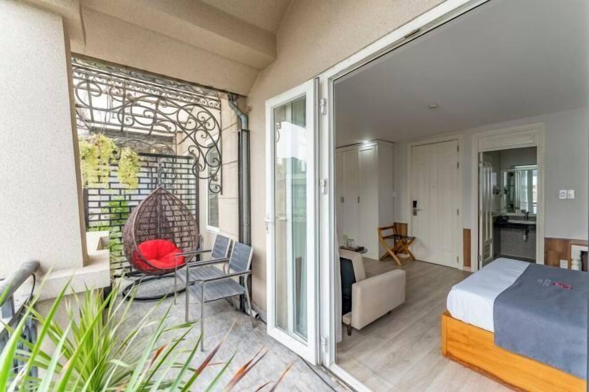 A modern room with a bed, a sofa, a chair, and a balcony with a decorative gate.