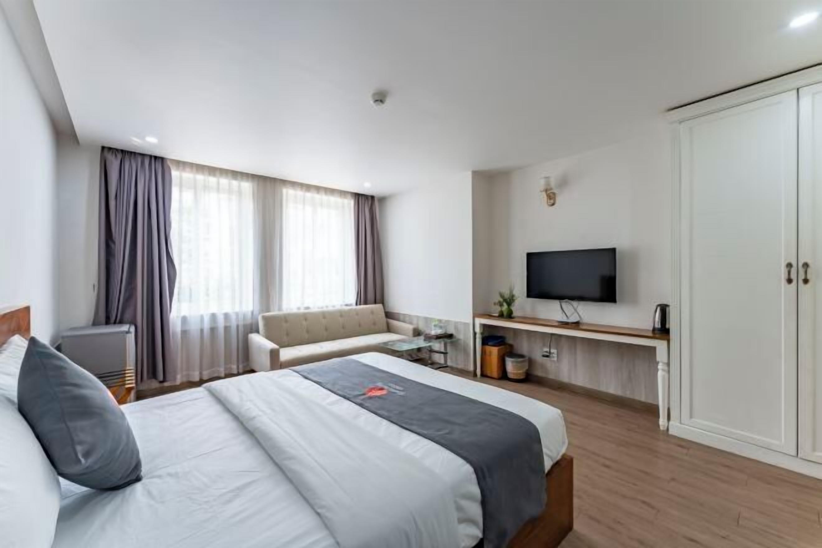 A hotel room with a bed, a sofa, a TV, and a wardrobe.