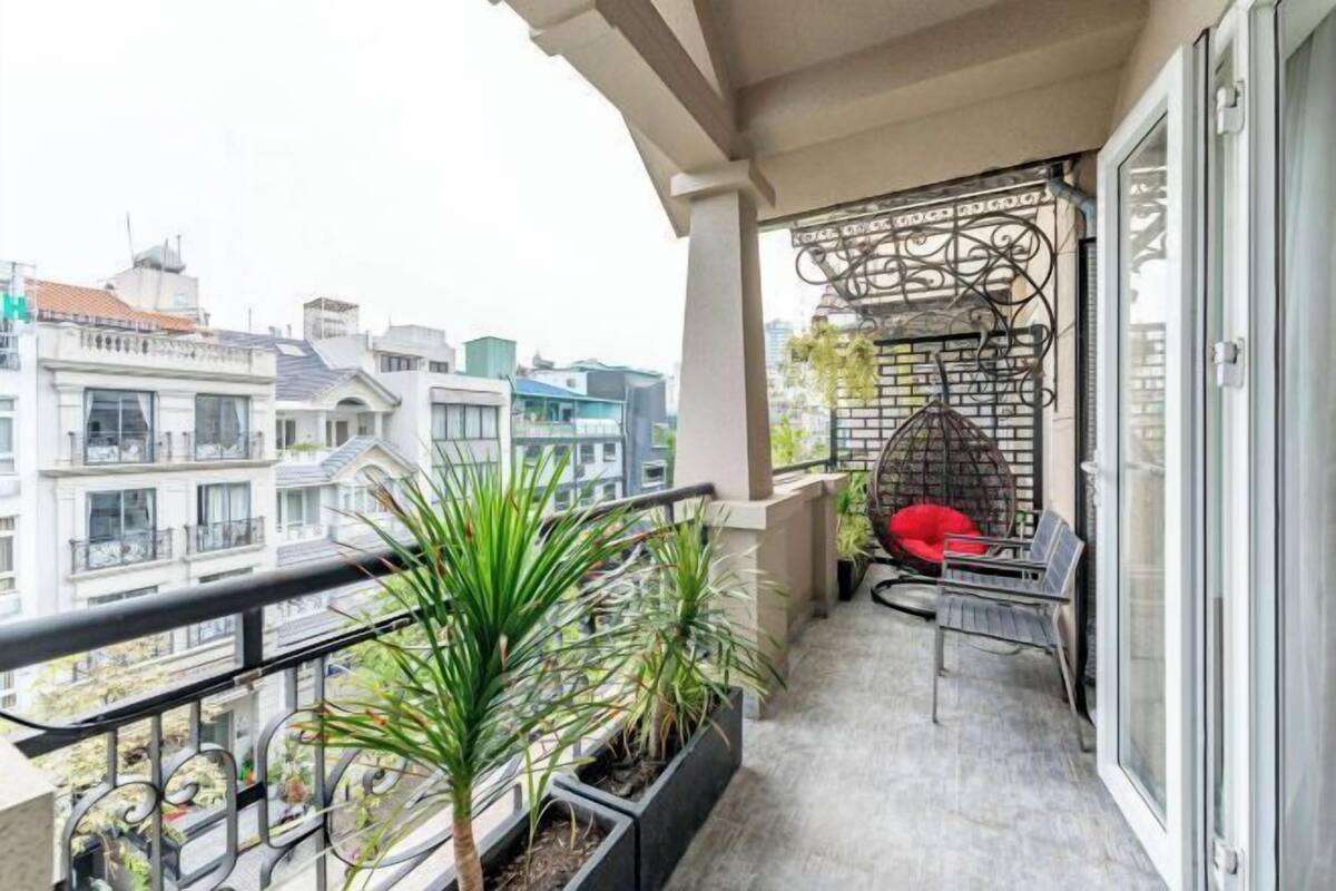 A balcony with potted plants, a red chair, and a metal decorative structure.