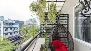 A balcony with a hanging chair, a view of the city, and a brick wall. - Edoya Hotel Phu My Hung (Ho Chi Minh City)