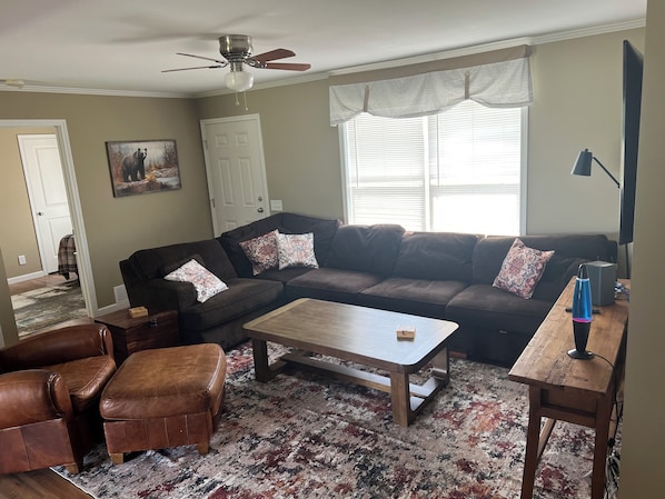 A living room with a brown leather couch, a wooden coffee table, and a patterned rug.