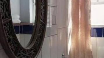 Un baño con lavamanos blanco, un espejo con marco decorativo, inodoro y cortina de ducha.