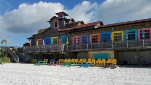 Een gebouw aan het strand met kleurrijke ramen en een overdekt zitgedeelte.