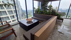 Un salon moderne avec une grande fenêtre, une table basse noire, un banc en bois et une plante en pot.