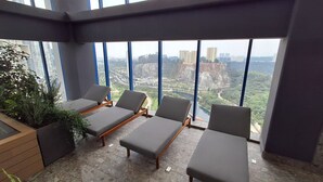 Un balcon avec quatre fauteuils de jardin gris et un bac à fleurs en bois agrémenté de plantes vertes.