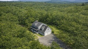 A large, two-story house with a wrap-around porch, surrounded by dense forest and hills in the background. - Private 5-Bed Country Estate on 22 Acres (Chester)