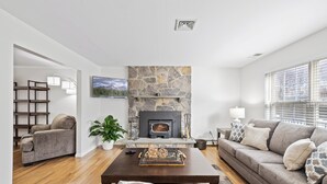 A modern living room with a stone fireplace, a sofa, a coffee table, and a television. - Private 5-Bed Country Estate on 22 Acres (Chester)