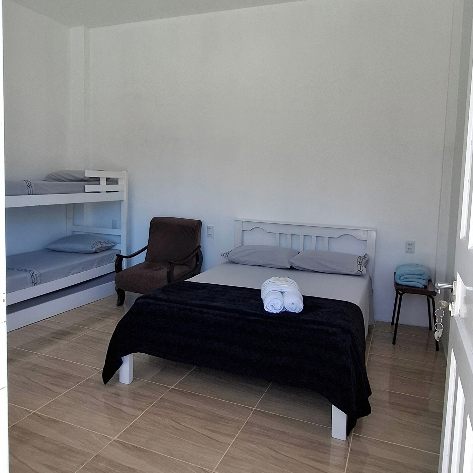 Una habitación con una cama, una silla y dos literas.