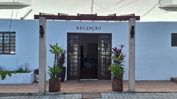 A reception area with a wooden pergola, potted plants, and a sign reading "RECEPCAO". - Pousada Felix (São Gabriel)