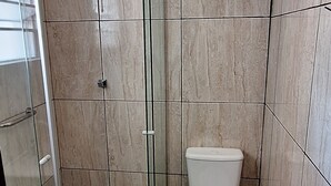 A bathroom with a glass-enclosed shower, a toilet, and a small trash bin. - Pousada Felix (São Gabriel)