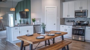 A modern kitchen with white cabinets, a wooden dining table with benches, a built-in oven, and a microwave. - Spacious 4BR Family Retreat- Comfort & Fun for All Ages (Shenandoah)