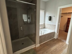 A modern bathroom with a glass-enclosed shower, a freestanding bathtub, and a wooden floor.