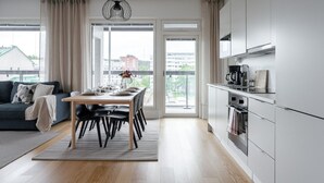 Een modern appartement met een eethoek, keuken en grote ramen met uitzicht over de stad.