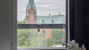 Een hotelkamer met een groot raam, met uitzicht op een kerk en een brug.