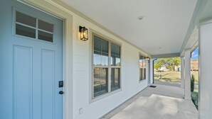 Une maison avec une porte bleu clair, un revêtement extérieur blanc et un porche couvert avec un luminaire.