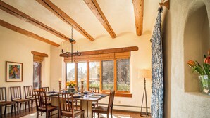 Zona pranzo con arredi in legno, ampie finestre e un lampadario.