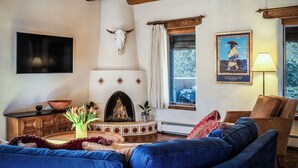 Un accogliente soggiorno con camino, televisore a parete e un'ampia finestra.