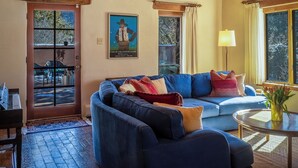 Un soggiorno accogliente con un divano blu, un soffitto in legno e una porta che dà sull'esterno.