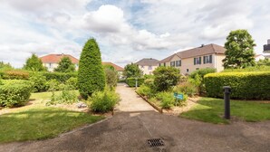 A residential street with houses, a well-maintained lawn, and a clear sky.